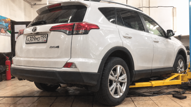 Белая Toyota RAV4 на подъёмнике в автосервисе АКППМИРGROUP